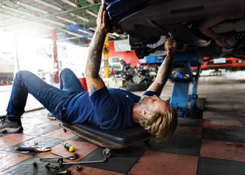Mechanic looking at the underside of a vehicle